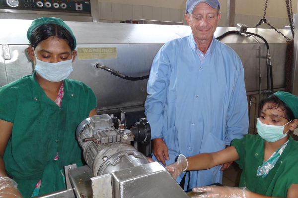 Volunteer Cliff Wener trains factory staff on new ways to prepare food.